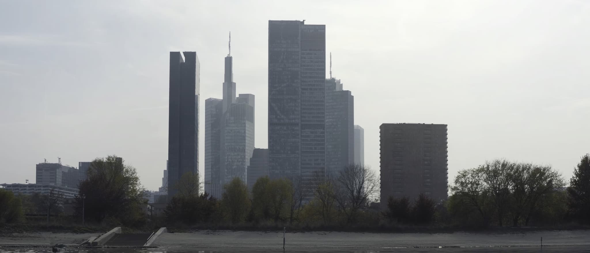 Das Mainufer, dahinter die Kanten der Hochhäuser im Dunst