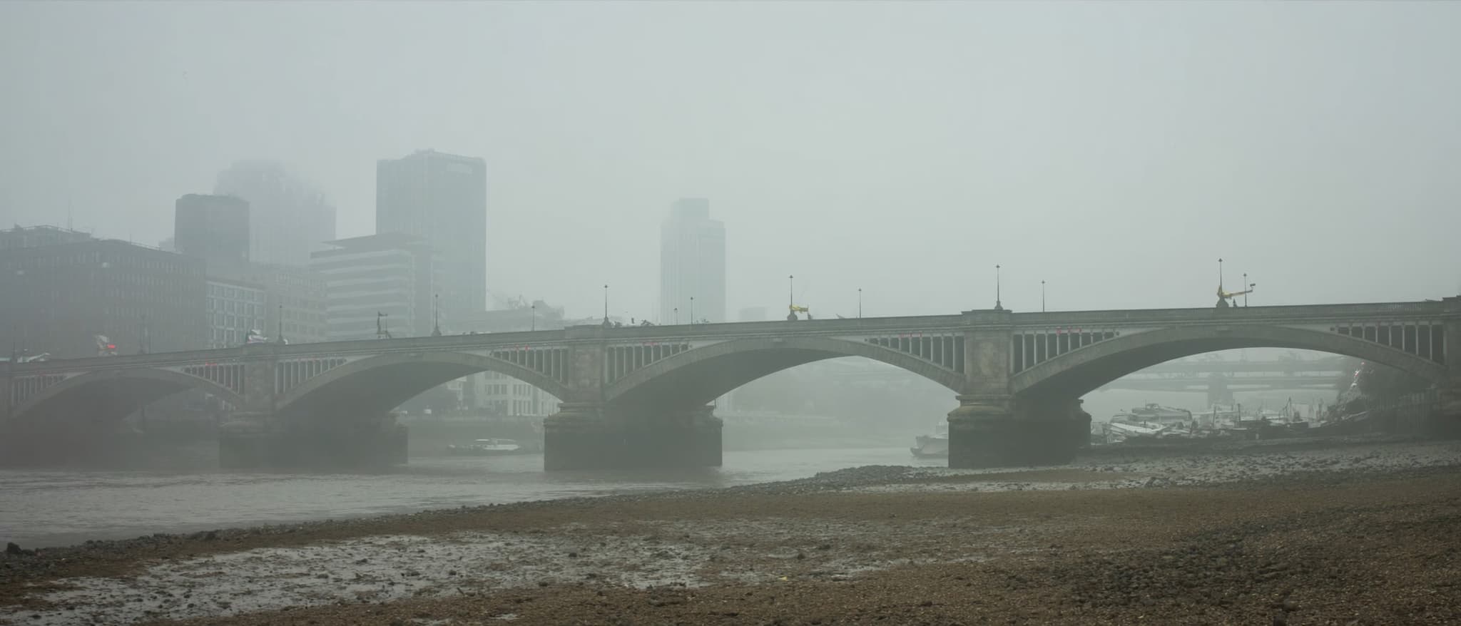 Die Themse bei Ebbe, eine Steinbrücke, die Türme der City im Dunst