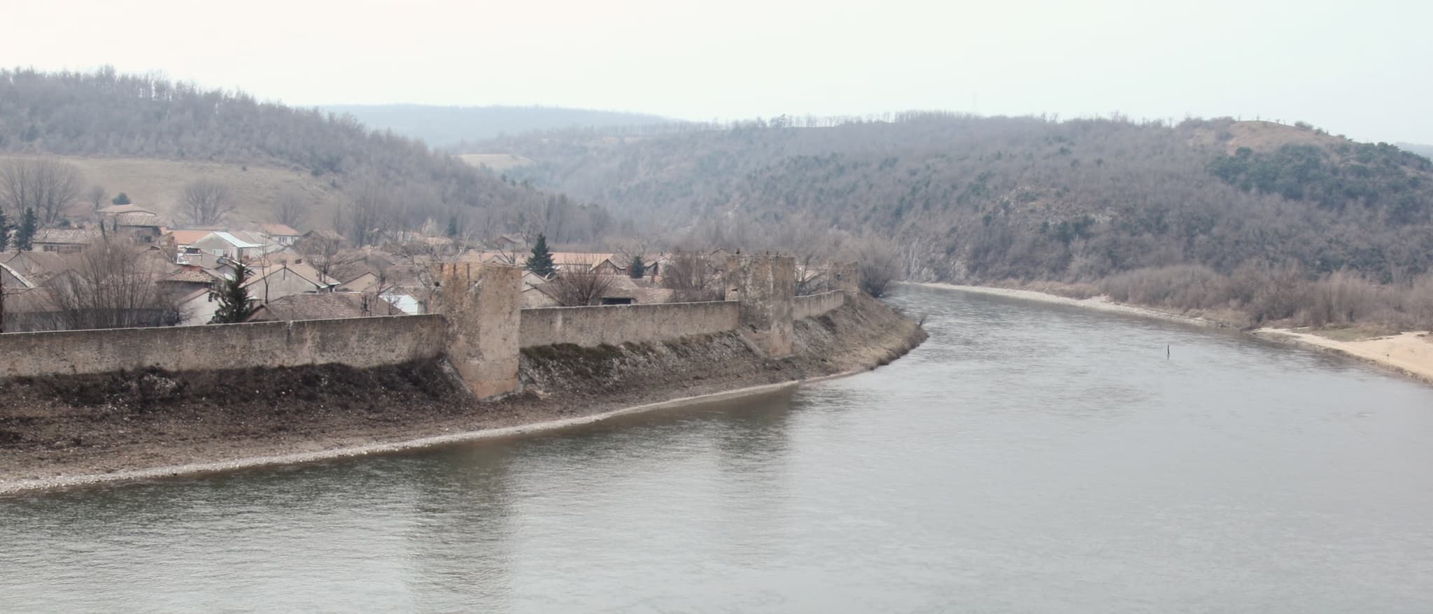 Der Fluss durch die niedrige Stadt, gerundete Hügel am Horizont